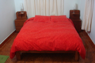 a bed with red sheets and pillows