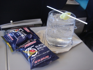 a glass of water with a slice of lemon on a stick next to a packet of chips