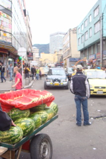 a man standing in a street with watermelons