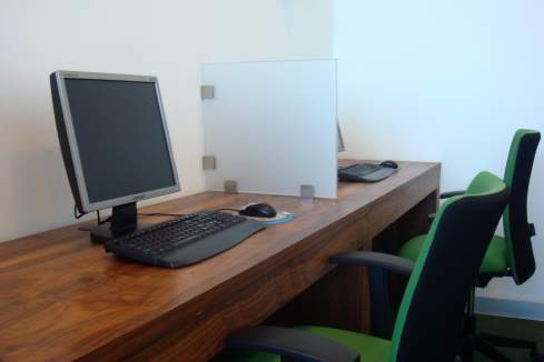 a desk with computers and a white screen