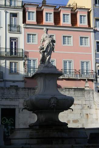 a statue of a woman in front of a pink building