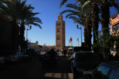 a tall tower with palm trees and people walking