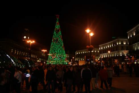a large crowd of people walking around a christmas tree