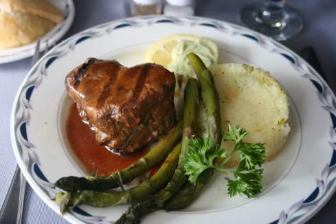 a heart-shaped steak with asparagus and potatoes on a plate