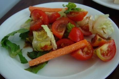 a plate of salad with tomatoes carrots and lettuce
