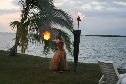 a man in grass skirt holding fire