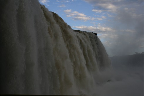 a large waterfall with clouds in the sky