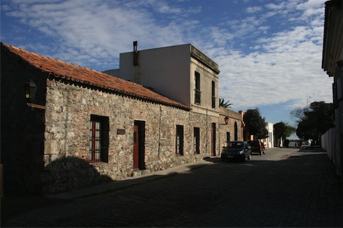 a stone building with a brick wall and a car parked on the side of it