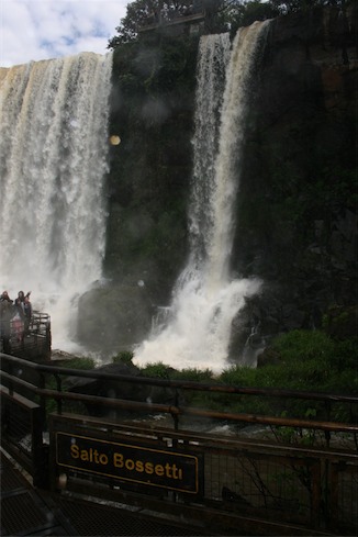 a waterfall with people standing on a railing