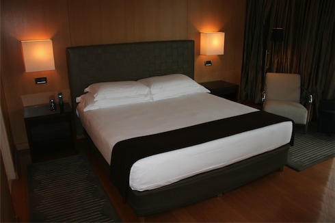 a bed with white sheets and a black blanket