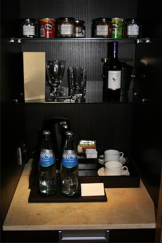 a cabinet with a few bottles of water and cups