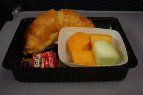 a croissant and fruit in a tray