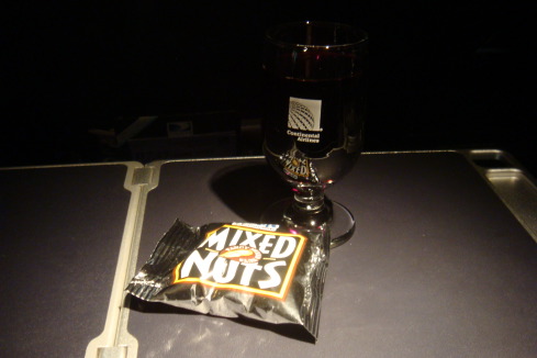 a glass of wine next to a bag of nuts