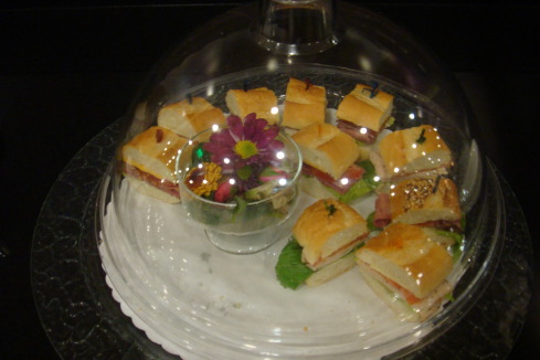 a tray of sandwiches and a small glass of flowers