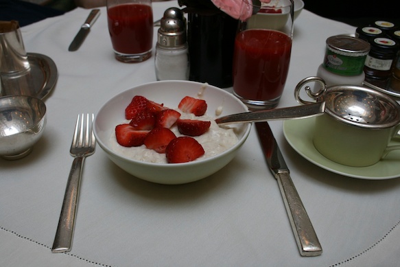 a bowl of strawberries and cream with a fork and knife