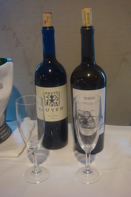 two bottles of wine next to a glass