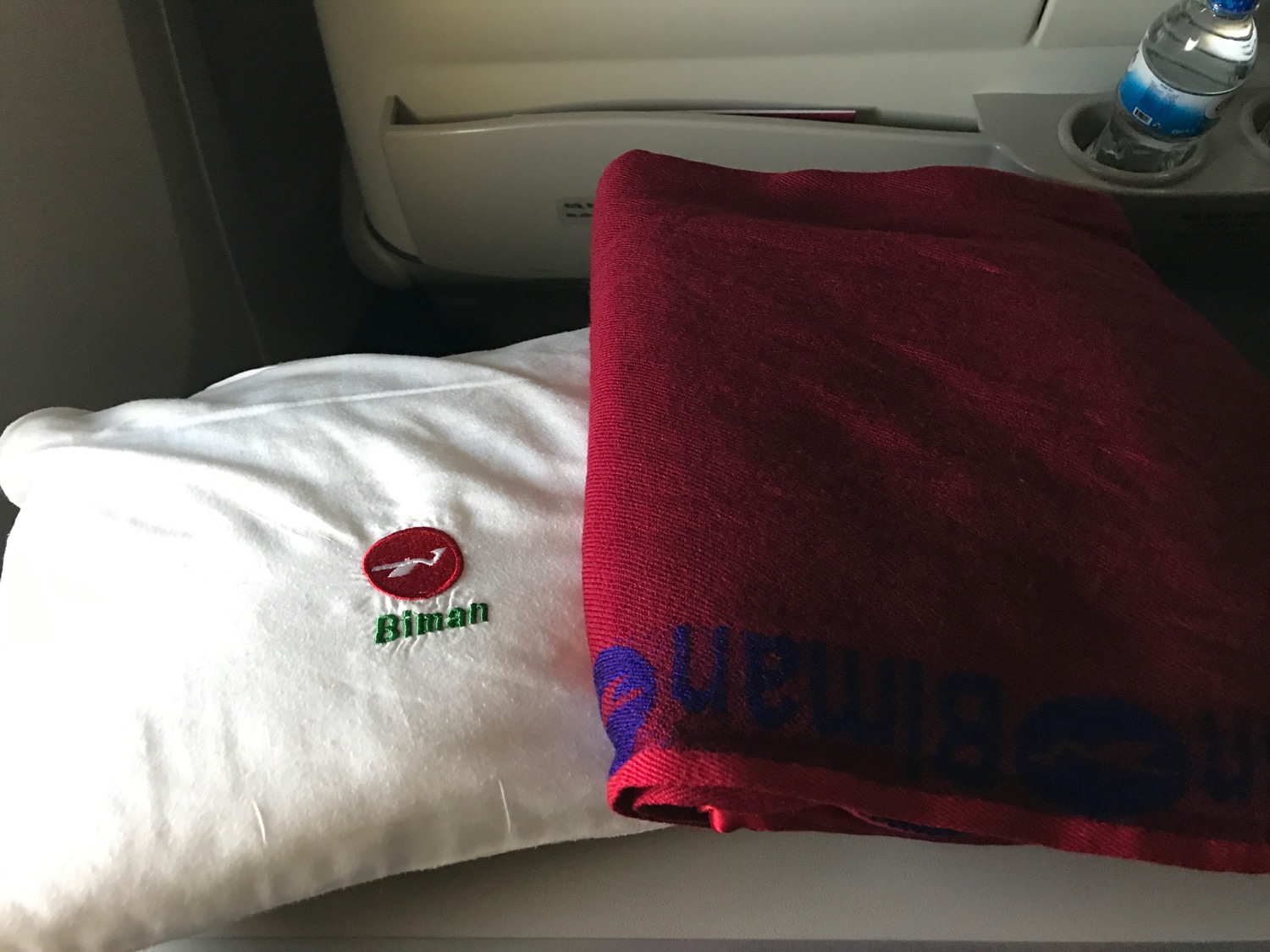 a white pillow and red blanket on a plane