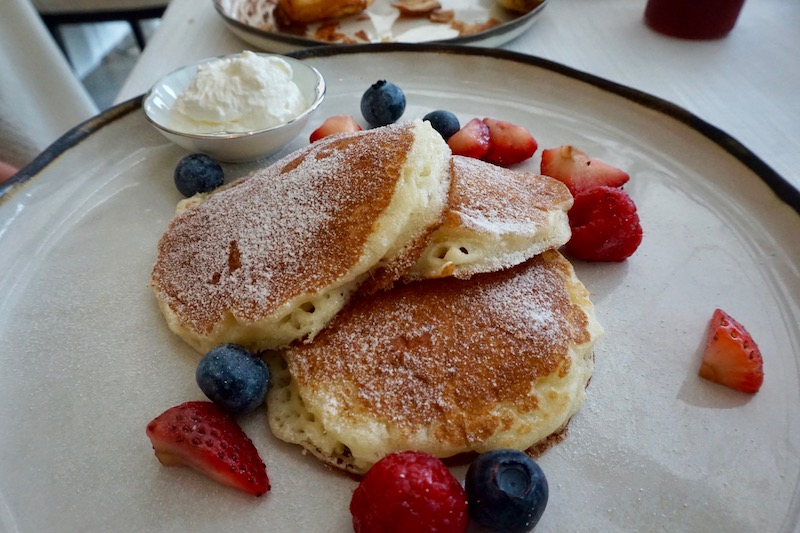 a plate of pancakes with berries and whipped cream