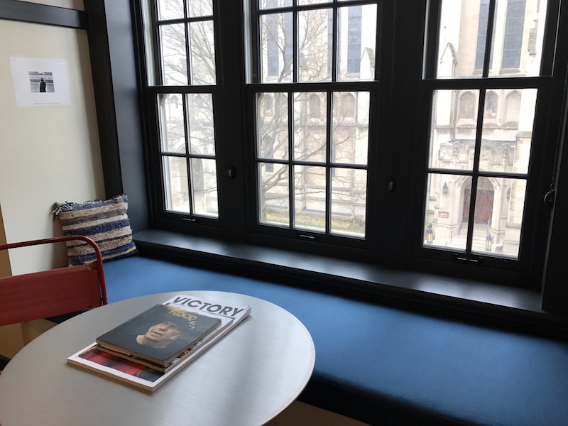 A sitting area by the window, artwork on the left wall, with the nearly 200 year-old church across the street.