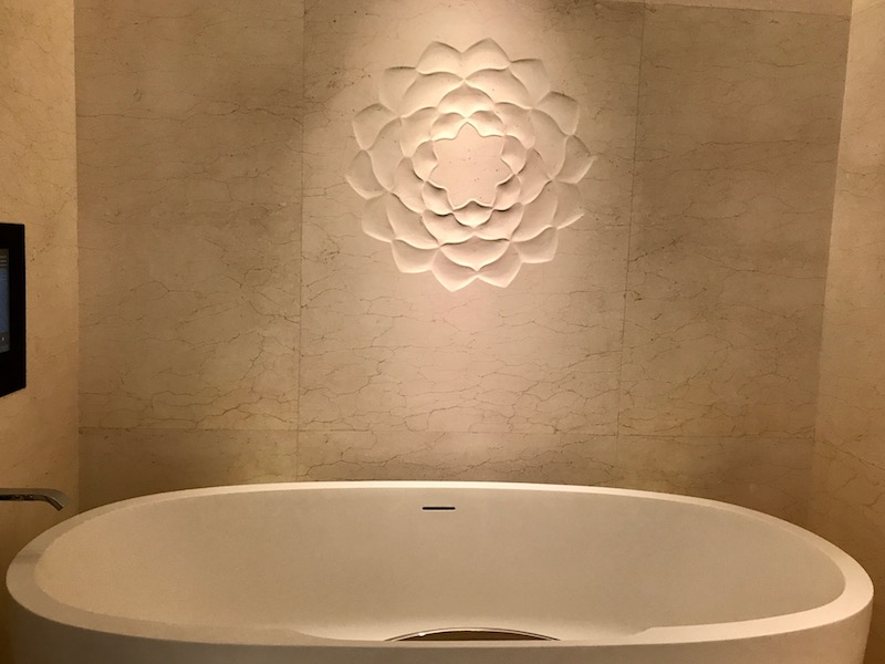 a white bathtub with a flower design on the wall