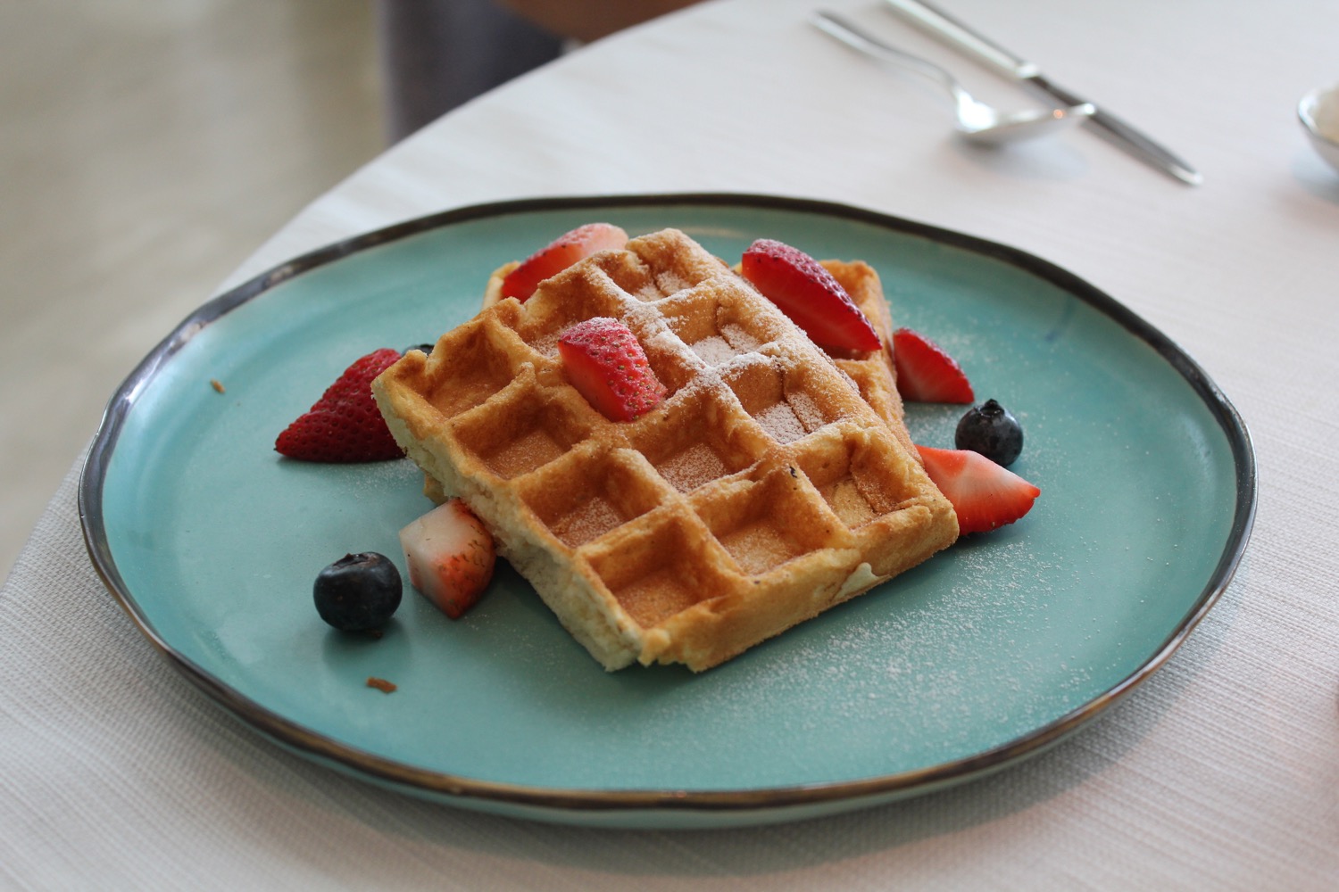 a waffle with strawberries and blueberries on a blue plate