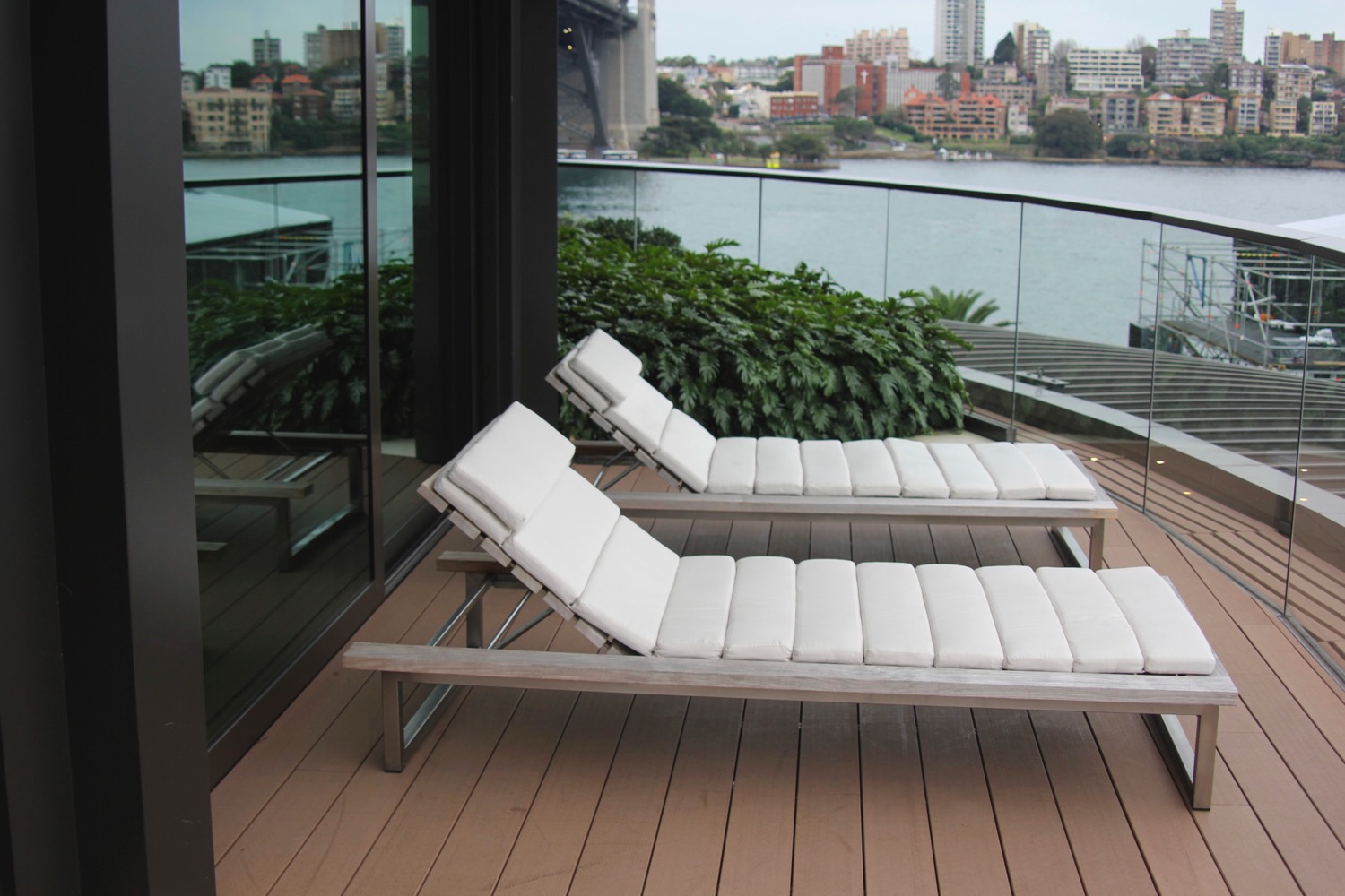 a couple of white lounge chairs on a deck overlooking a body of water