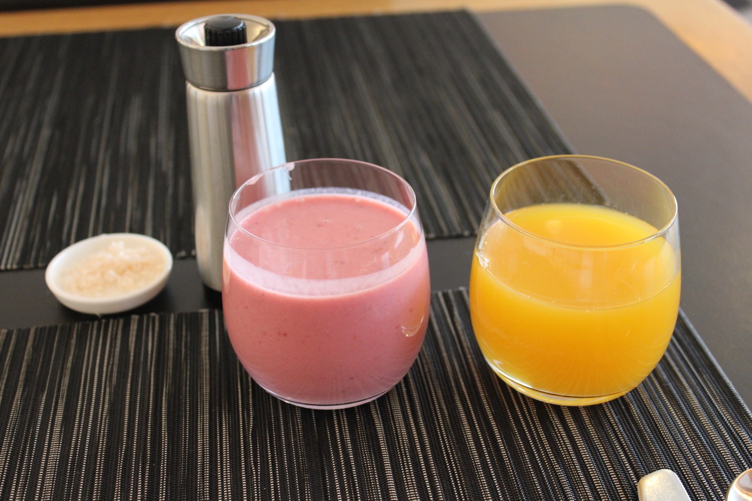 a glass of juice and a shaker on a place mat