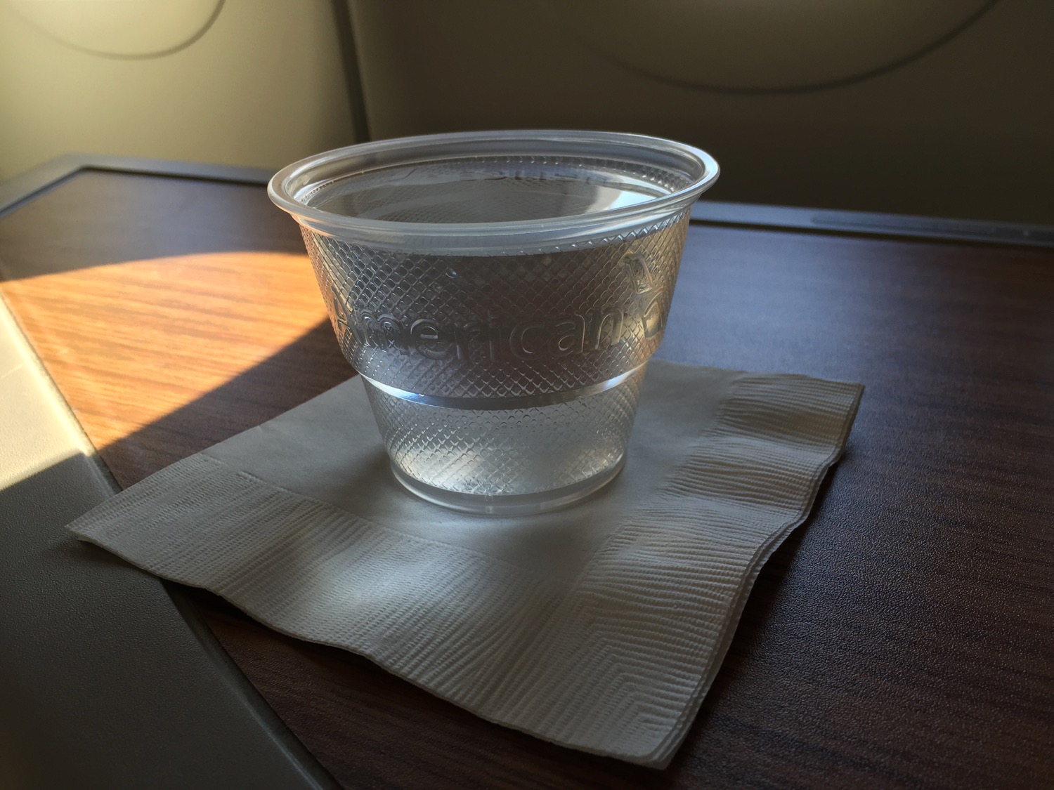 a clear plastic cup with water on a napkin on a table