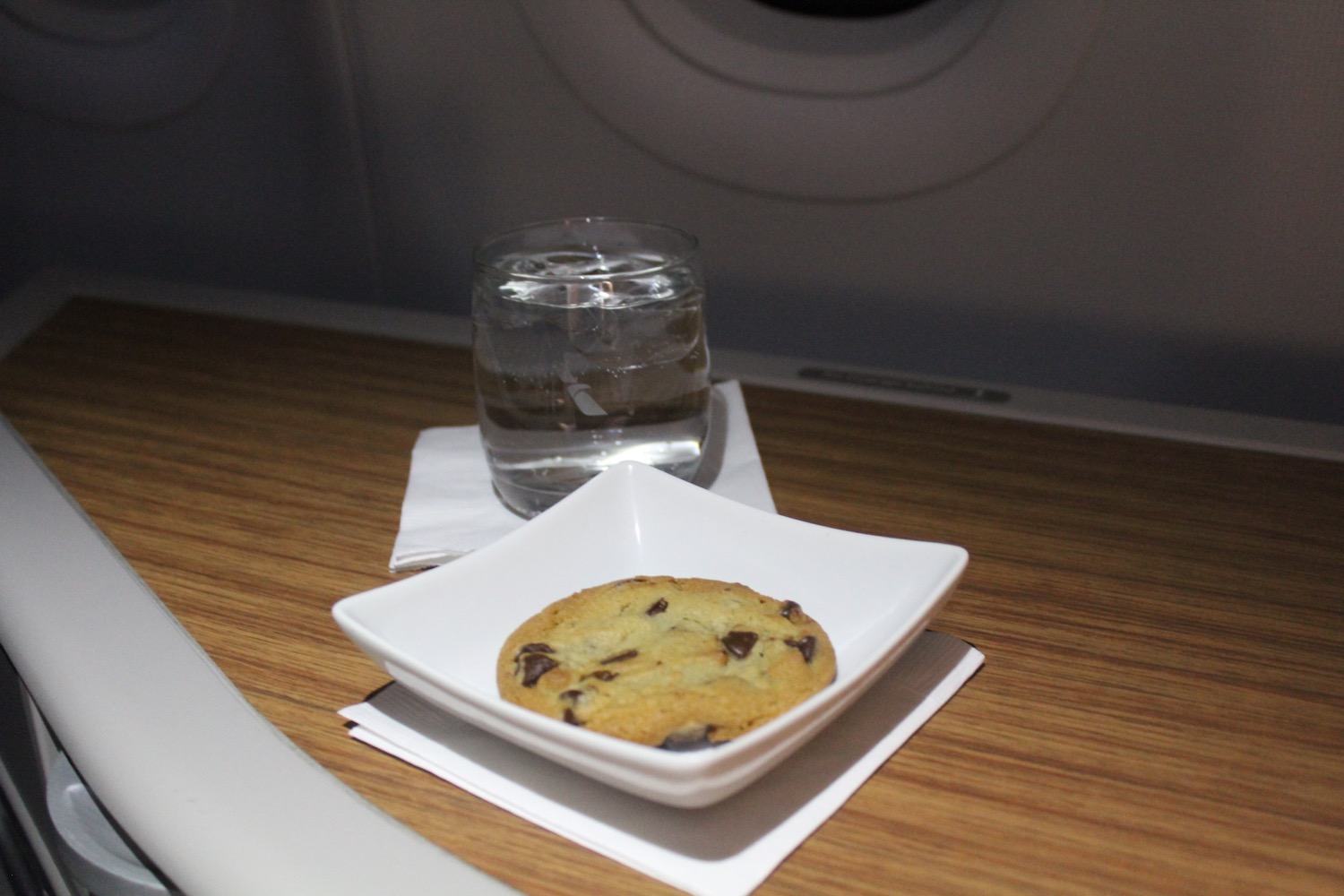 a cookie in a square bowl next to a glass of water