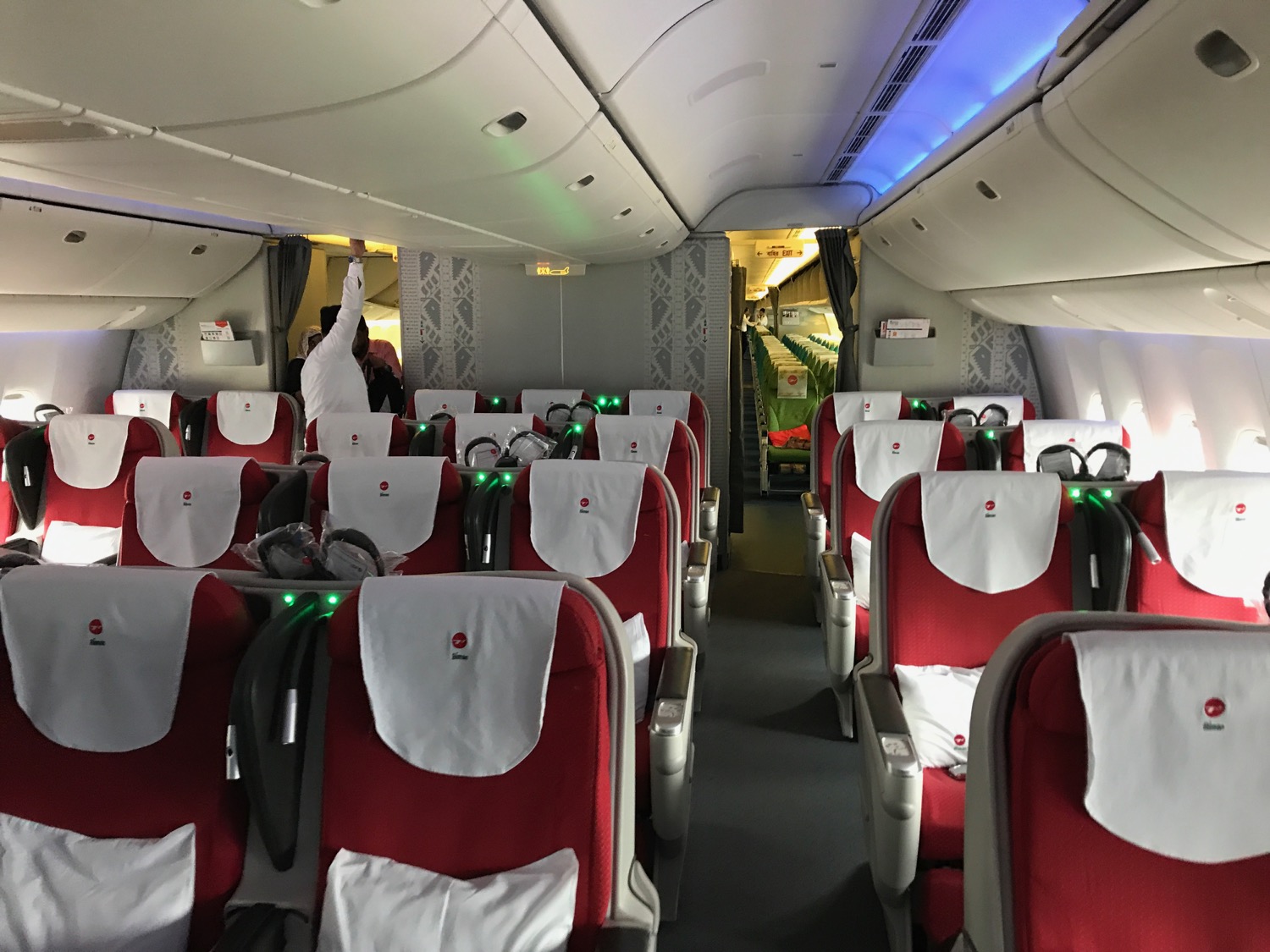 the inside of an airplane with red seats and white sheets