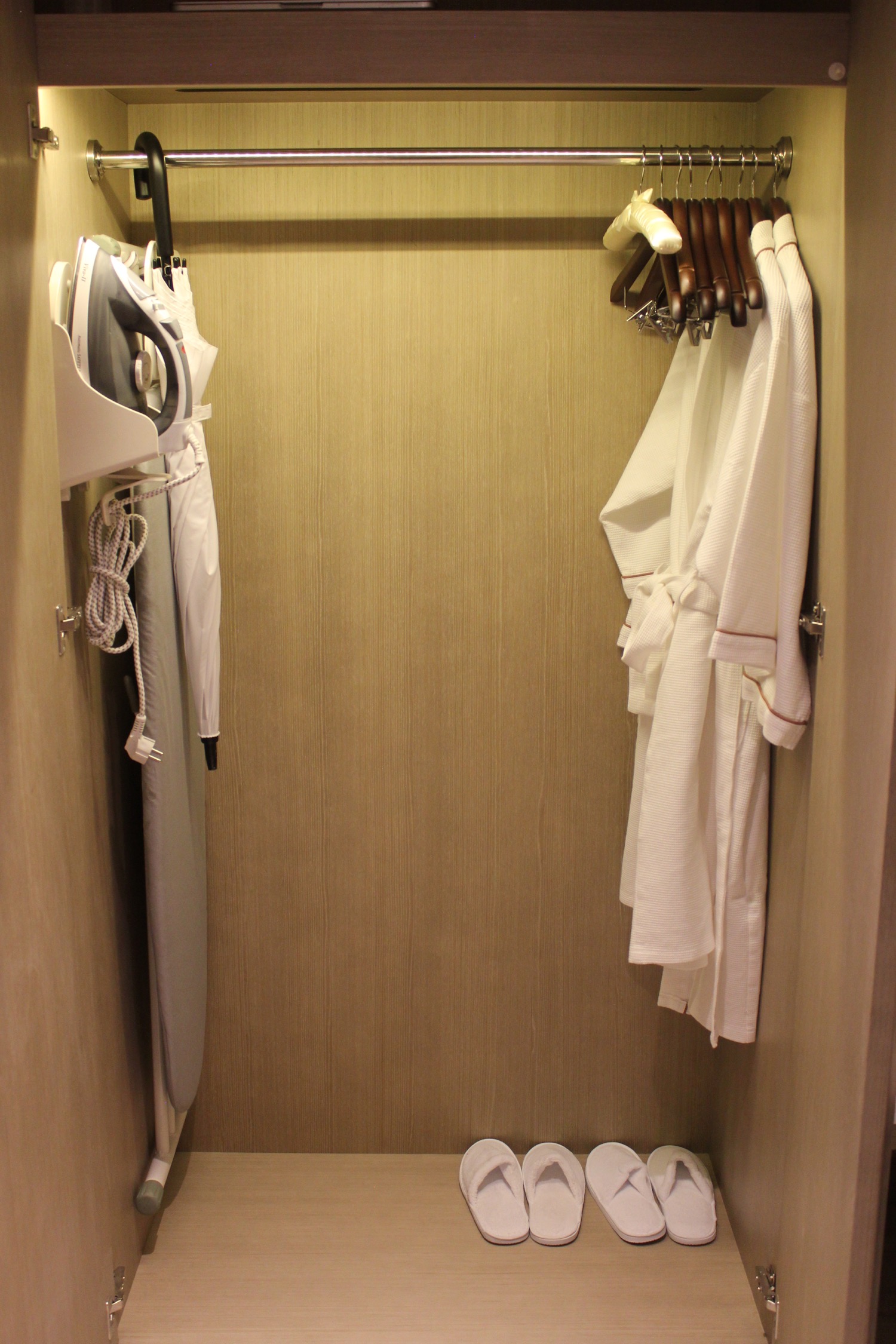 a room with white robes and ironing board