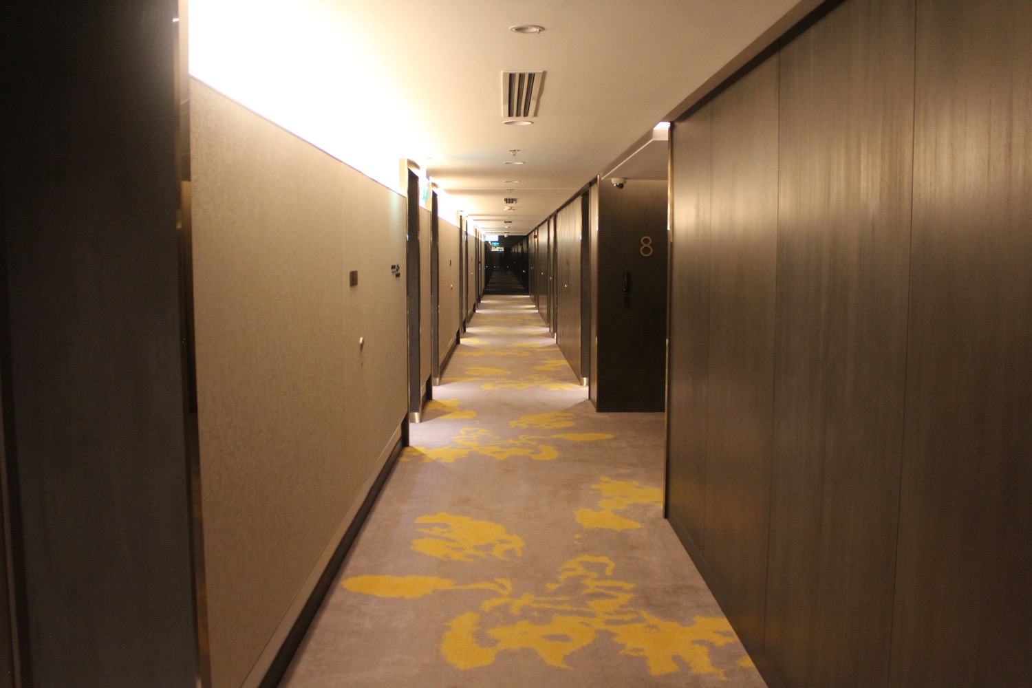a long hallway with doors and yellow carpet