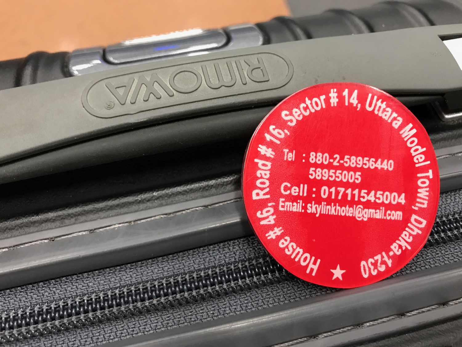 a red round sticker on a black suitcase