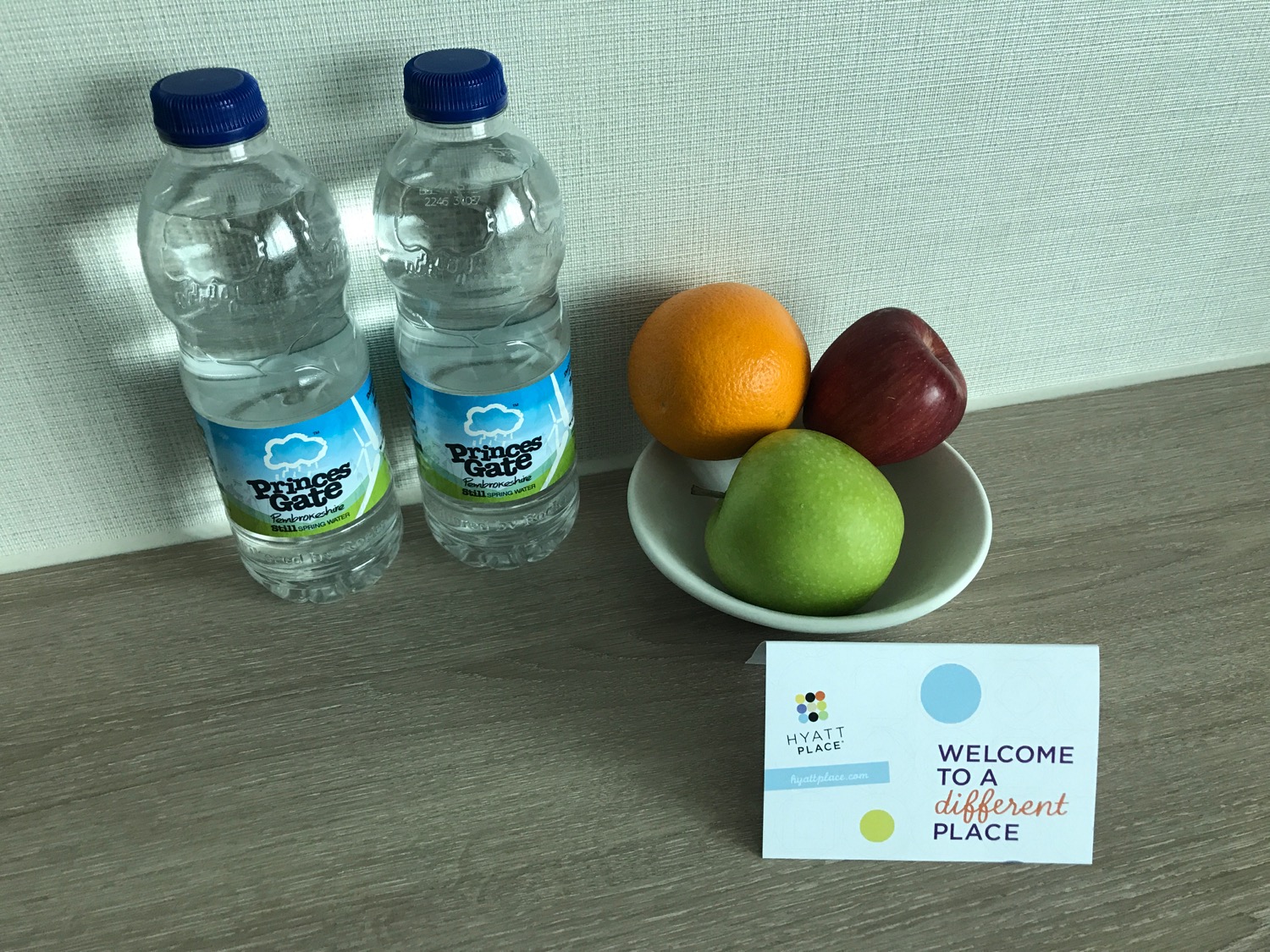 a bowl of fruit and two bottles of water next to a sign