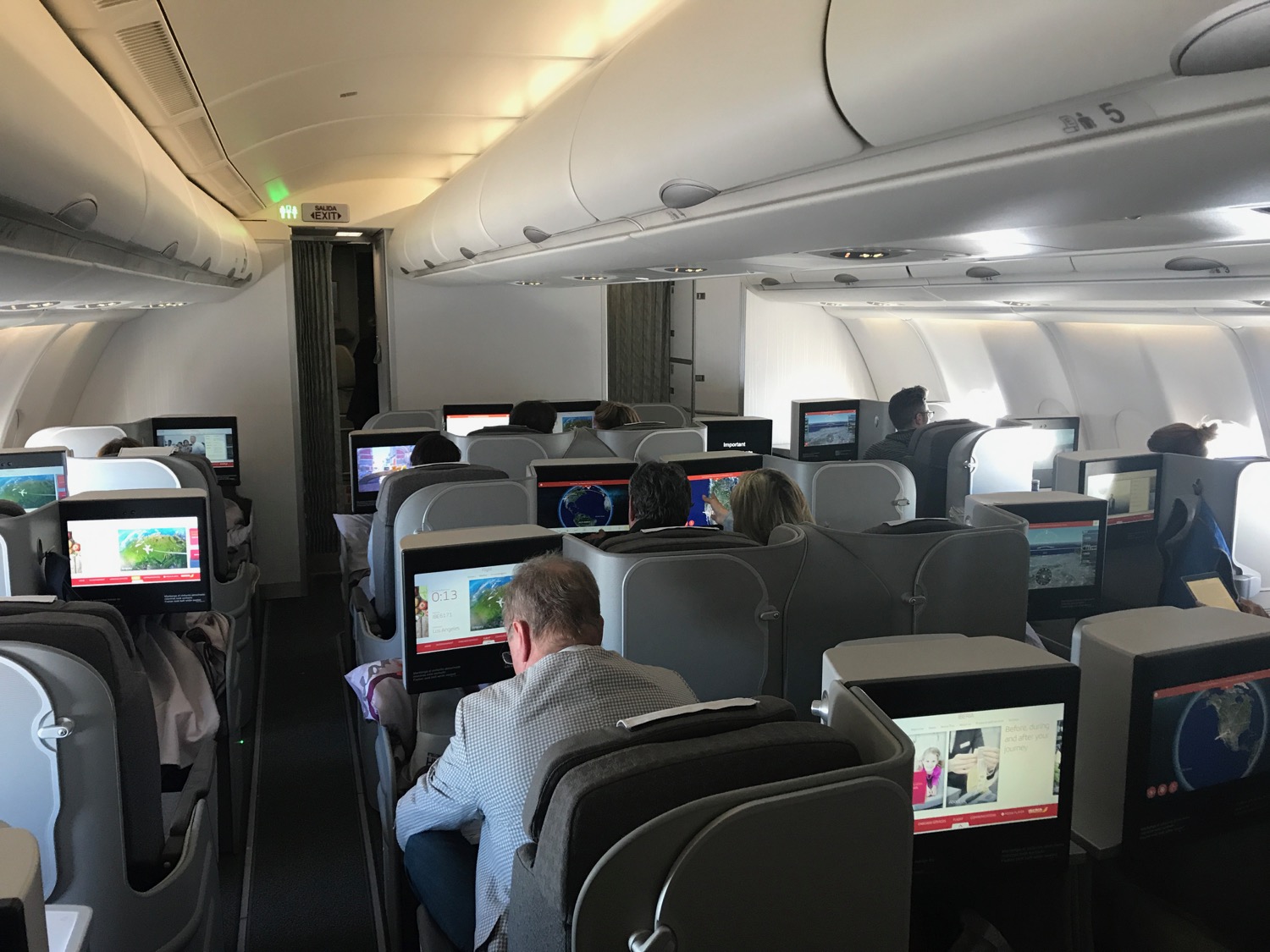 people sitting in an airplane with many monitors