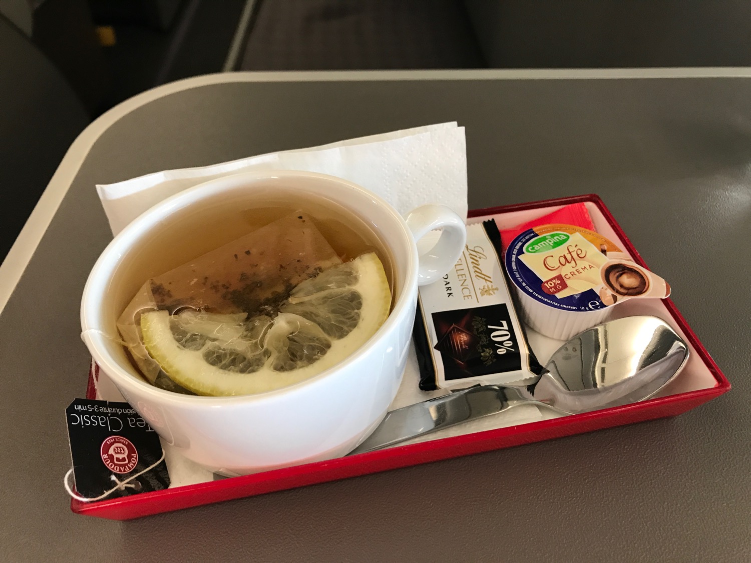 a cup of tea with lemon slices and a spoon on a tray