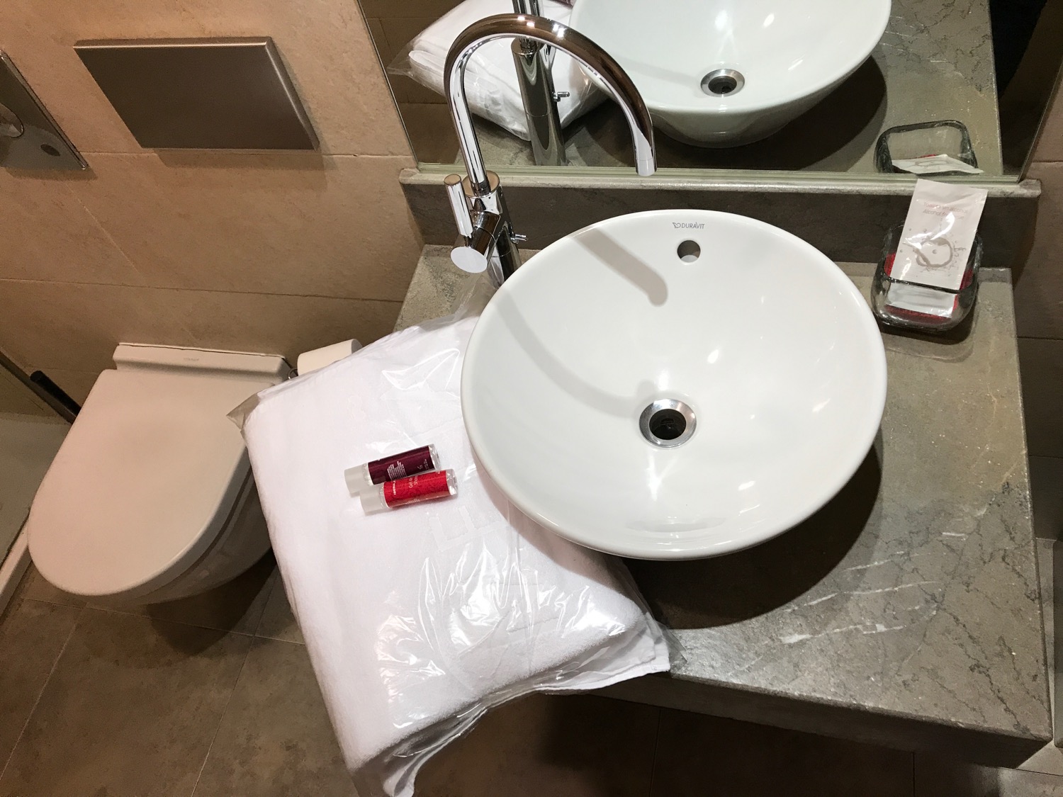 a bathroom sink with a toilet and lipstick on the counter