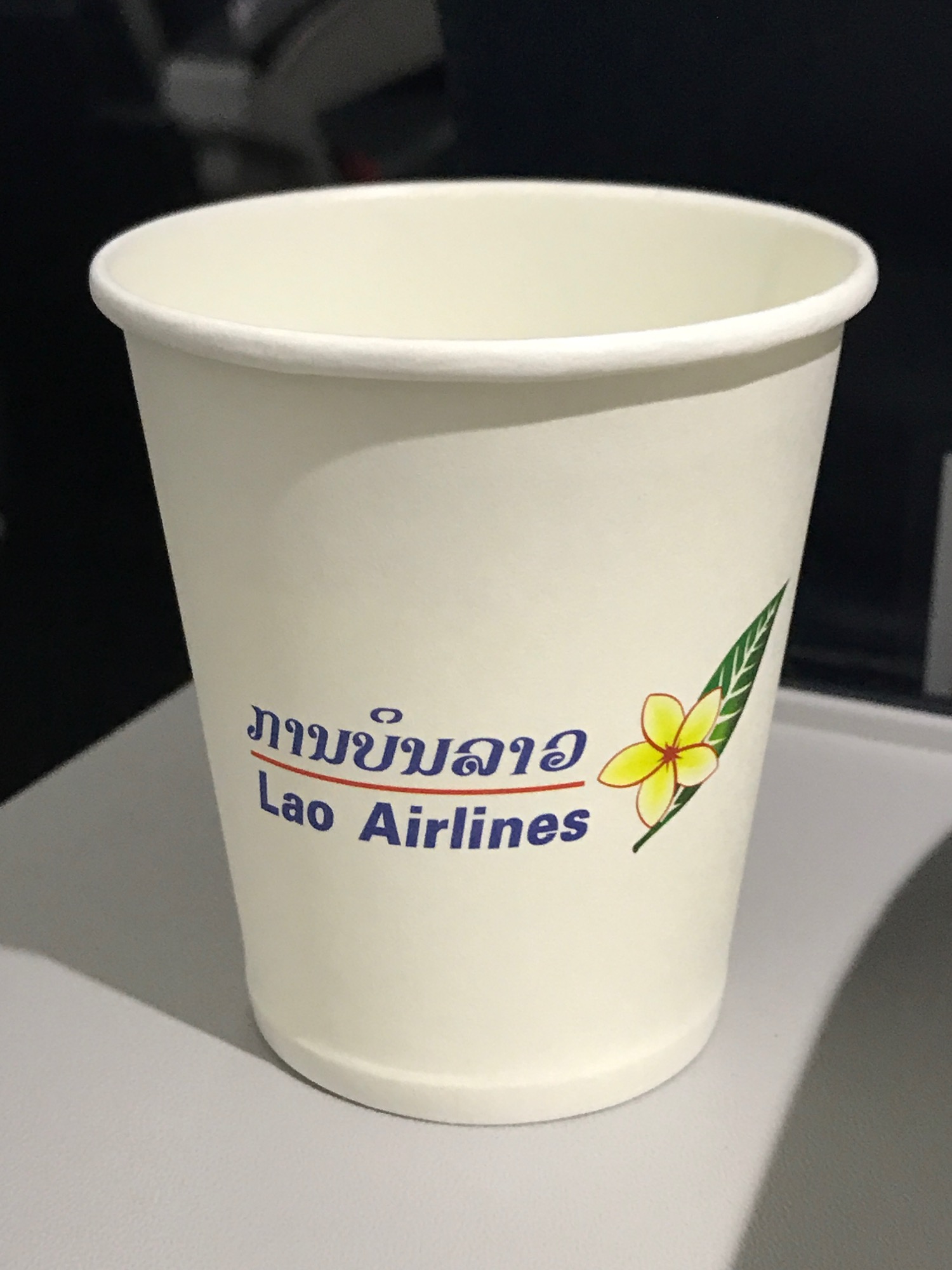 a white paper cup with blue text and a flower on it