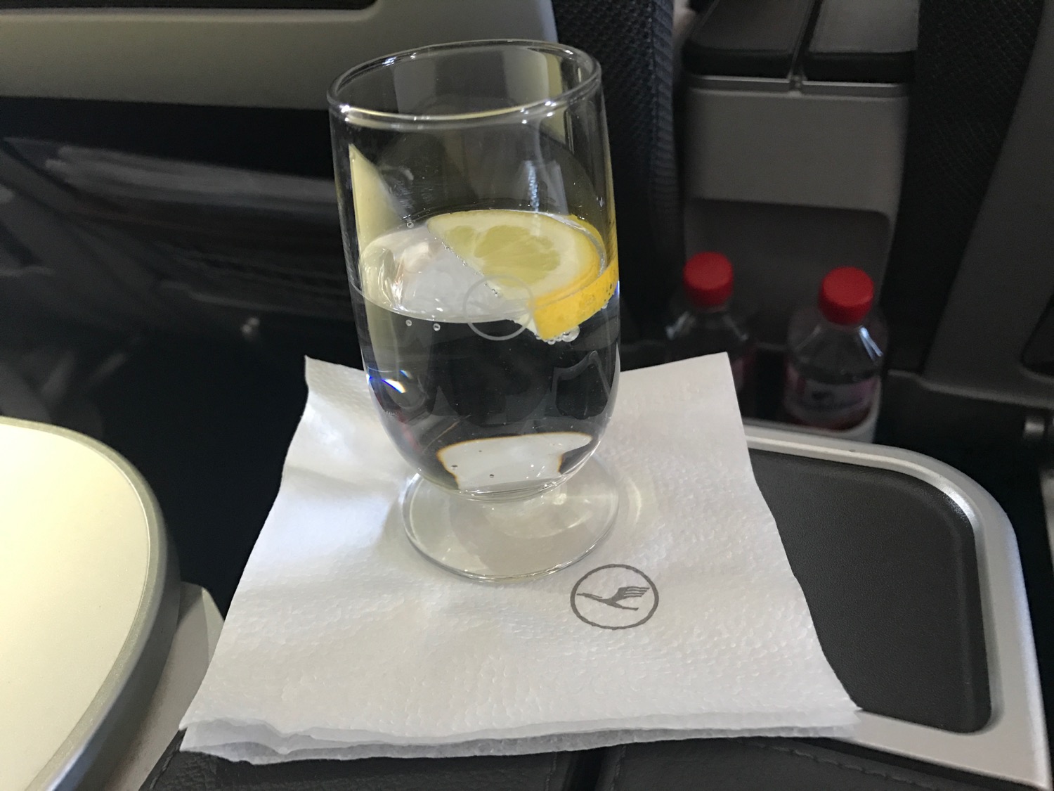 a glass of water with a lemon slice on a napkin on a seat