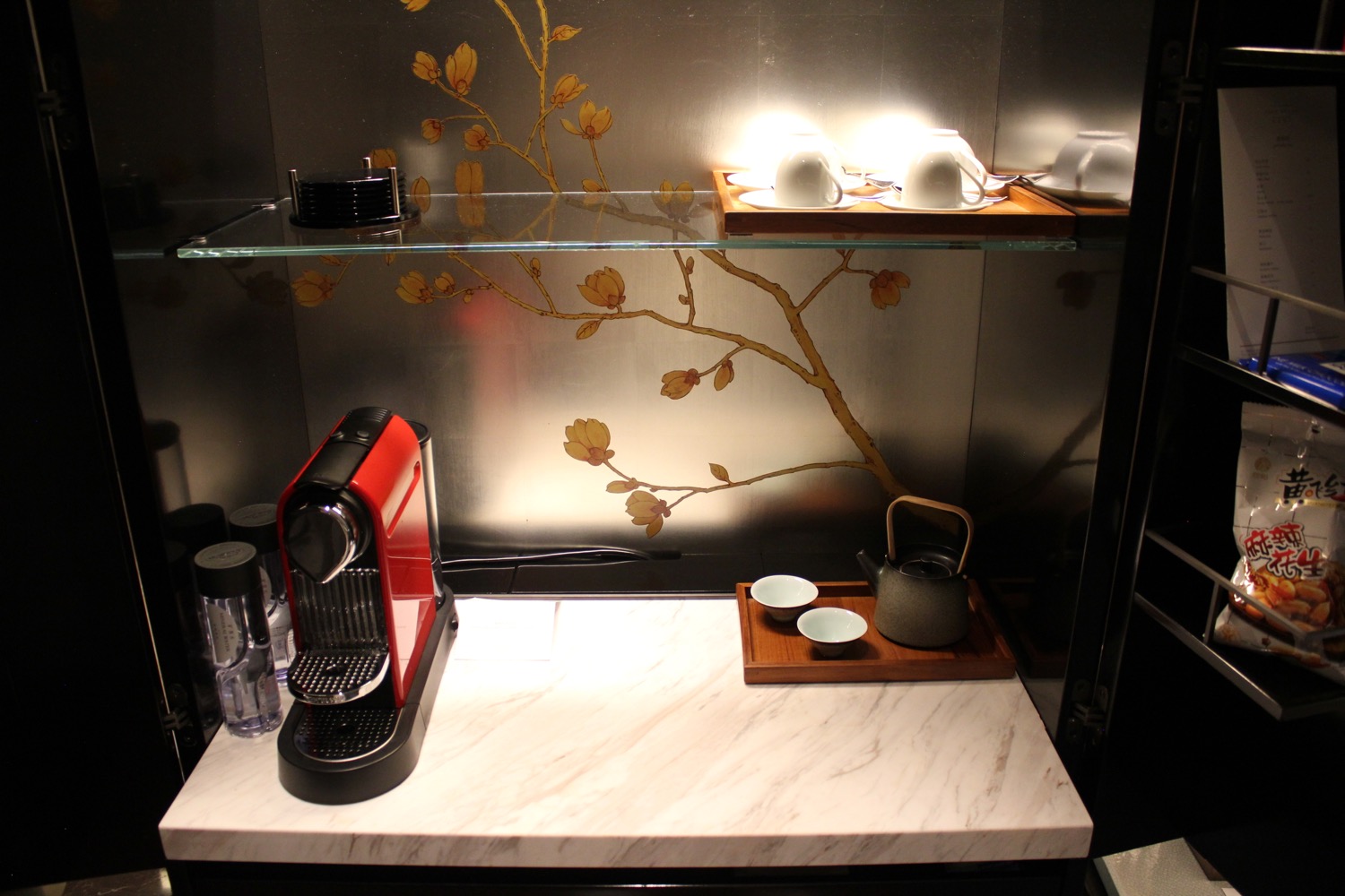 a glass shelf with a coffee machine and teapots on it
