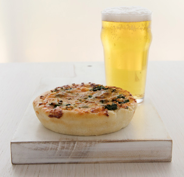 a pizza on a cutting board next to a glass of beer
