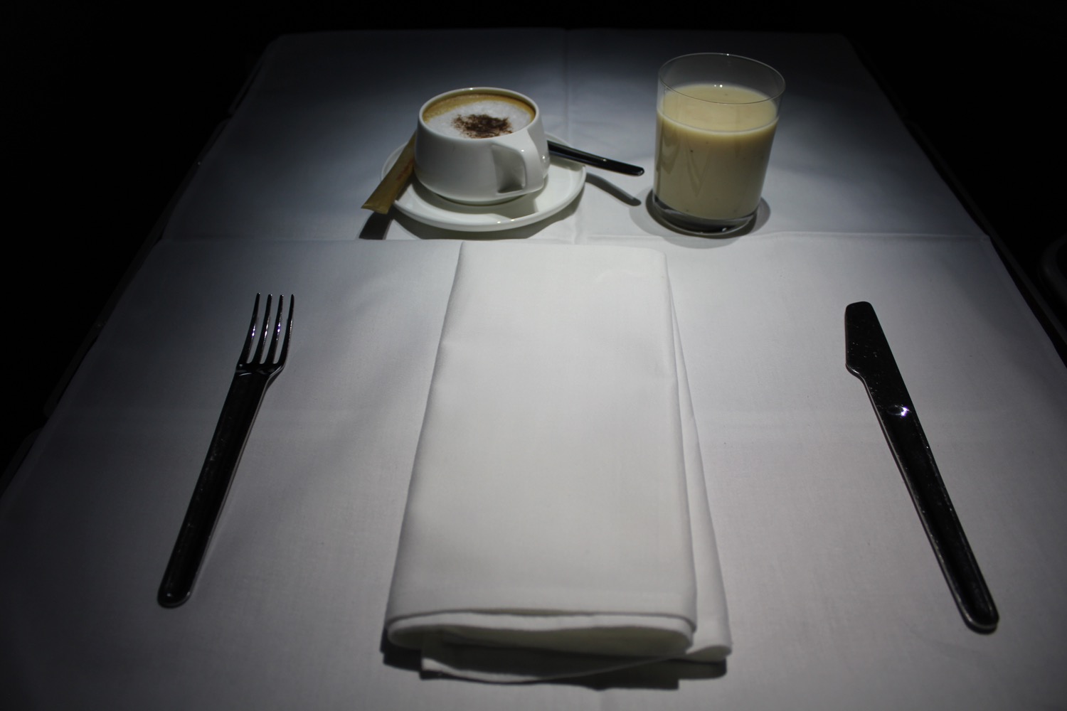 a white napkin and a cup of coffee on a white table