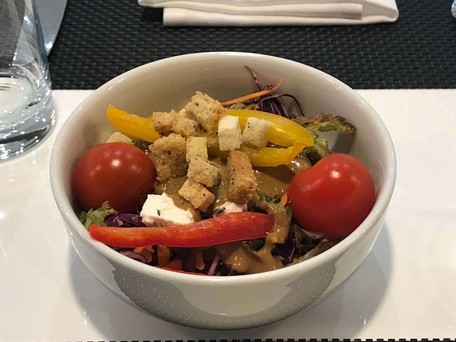a bowl of salad with tomatoes and croutons