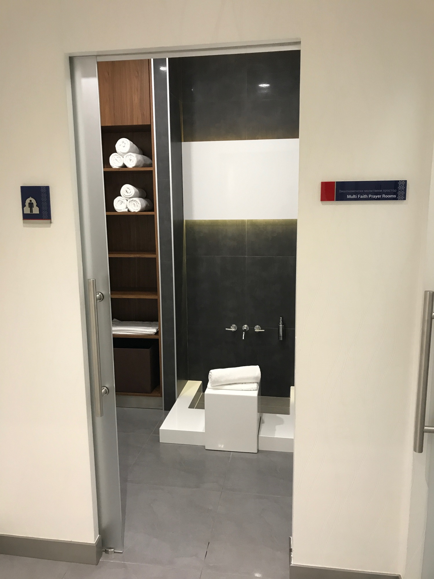 a bathroom with a shower and a shelf with towels