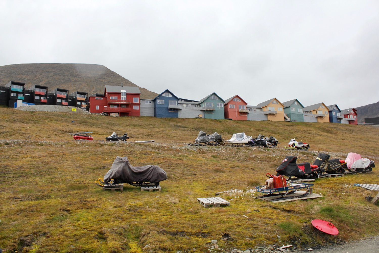 a group of houses and snowmobiles on a hill