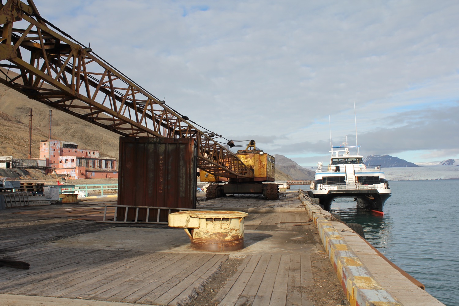 a large metal structure on a dock with a boat in the background