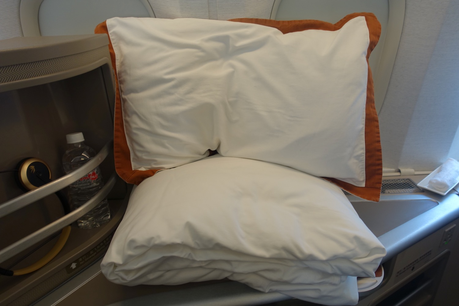 a white and orange pillow on a bed