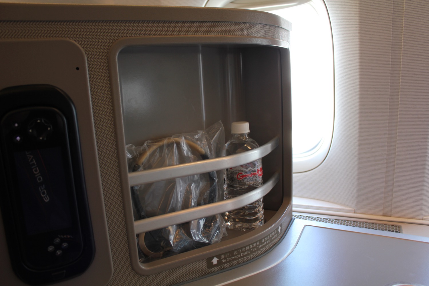 a plastic bottle and a bag inside a shelf on an airplane