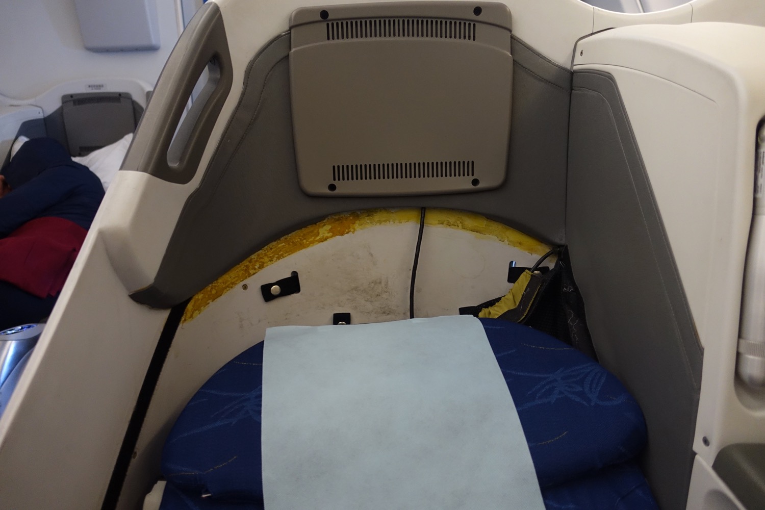 a seat with a blue blanket and a white sheet in the back