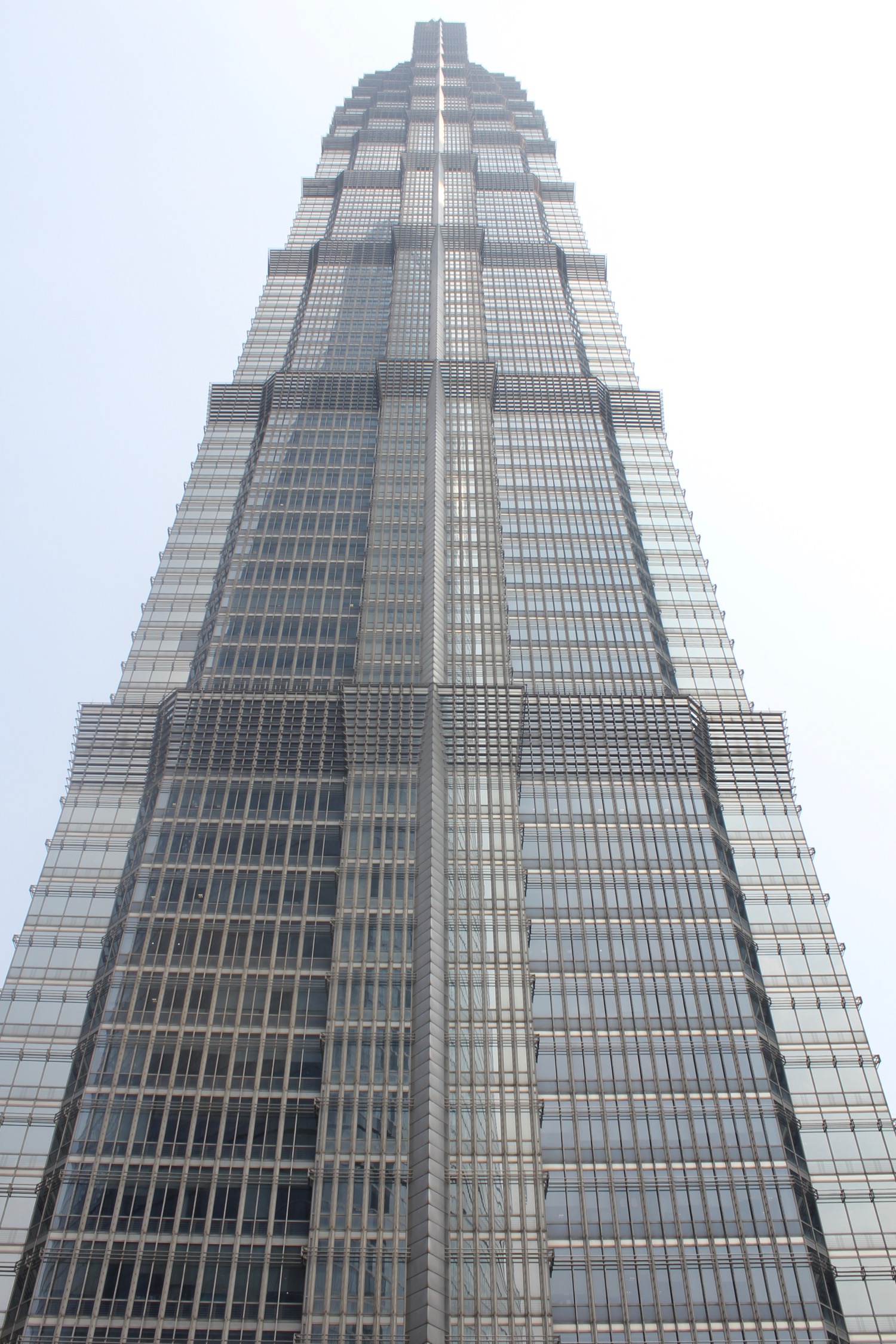 a tall building with many windows with Jin Mao Tower in the background